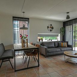 Gemuetliches Wohnzimmer des Ferienhauses Busch en Dam in Uitgeest, Nordholland, mit moderner Einrichtung und Blick auf den Garten.