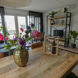 Gemuetliches Wohnzimmer im Ferienhaus Busch en Dam in Uitgeest, Nordholland, mit moderner Einrichtung und Blick auf den Garten.