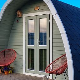 Gezellige veranda van Huisje in Zuid-Scharwoude, een vakantiehuis in Noord-Holland, met uitzicht op de groene omgeving.