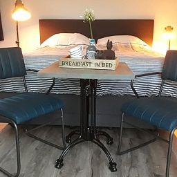Gemuetliches Schlafzimmer in einem Ferienhaus in Nieuw Vennep, Nordholland, mit komfortabler Sitzecke und Fruehstuecksservice.