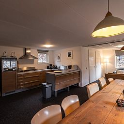 Geraeumiges Wohnzimmer von Huisje in Den Ham, Ferienhaus in Twente, Overijssel, mit gemuetlicher Sitzecke und langem Esstisch fuer Familienaufenthalte.