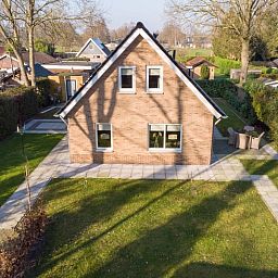 Buitenkant van Vakantiehuisje in Den Ham, Twente, omringd door groene tuin en charmante paden.
