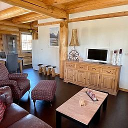 Gemuetliches Wohnzimmer im Ferienhaus in Den Ham, Twente, Overijssel. Inneneinrichtung aus Holz mit bequemen Sitzgelegenheiten und rustikalem Charme.