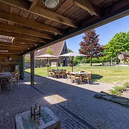 Gemuetliches Wohnzimmer im Ferienhaus in de Lutte, Twente, mit buntem Sofa, Holzofen und grossem Esstisch fuer einen komfortablen Aufenthalt.