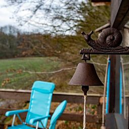 Veranda des Ferienhauses in De Lutte in Twente mit Blick auf gruene Felder und eine rustikale Blase in Overijssel.