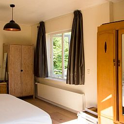 Attraktives Schlafzimmer im Ferienhaus in De Lutte, Twente, mit Holzmoebeln und Blick auf die gruene Umgebung von Overijssel.