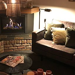 Gemuetliches Wohnzimmer im Cottage in Weerselo, Twente mit Kamin und bequemem Sofa.