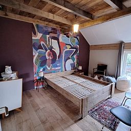 Gemuetlicher Innenraum des Ferienhauses in Tilligte, Twente, mit authentischen Holzbalken und einem stimmungsvollen Holzofen.