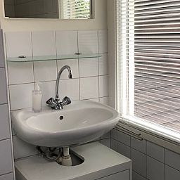 Modernes Badezimmer in Cottage in Haaksbergen, Ferienhaus in Twente, Overijssel mit Waschbecken und natuerlichem Licht durch grosse Fenster.