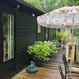 Gezellige veranda van Huisje in Haaksbergen, vakantiehuis in Twente, Overijssel, omringd door groene natuur en comfortabele zitgelegenheid.