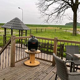Zicht op de groene omgeving vanaf het terras van Vakantiehuisje in Markelo, Twente, Overijssel met comfortabele zitplaatsen.