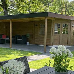 Geraeumige Terrasse mit Sonnenschirm im Ferienhaus DG630 in Denekamp, Twente, umgeben von viel Gruen.