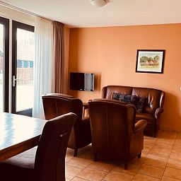 Gemuetliches Wohnzimmer im Ferienhaus in Denekamp, Twente, mit komfortabler Sitzecke und Essecke, ideal fuer entspannte Familienurlaube.