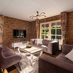 Cozy living room in Holiday Home in Losser, Twente, Overijssel with comfortable sofas and garden view.
