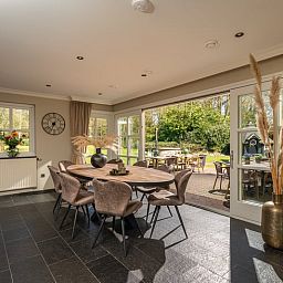 Gezellige eetruimte in Huisje in Losser, vakantiehuis in Twente, Overijssel met uitzicht op de groene tuin en terras.