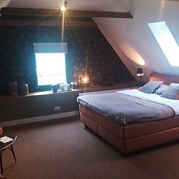 Gemuetliches Schlafzimmer im Huisje in Losser, einem Ferienhaus in Twente, Overijssel, mit einem bequemen Bett und stimmungsvoller Beleuchtung.