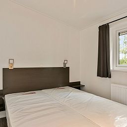 Cozy bedroom in vacation home IJssel 6, Hoge Hexel, Twente with two beds and views of the green surroundings.