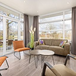 Stylish living room of vacation home Regge 6 in Hoge Hexel, Twente. Enjoy the view of the green surroundings and the inviting terrace.