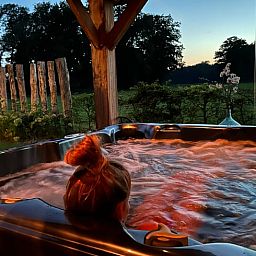 Ontspannen in de jacuzzi bij zonsondergang in Vakantiehuisje in Agelo, midden in de natuur van Twente, Overijssel.