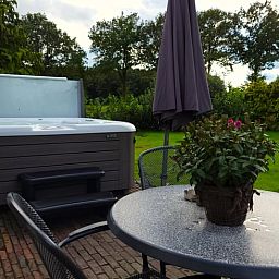 Entspannen Sie sich im Jacuzzi auf der Terrasse des Ferienhauses in Lonneker, Twente, mit Blick auf die gruene Umgebung.