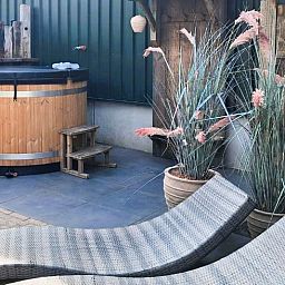 Relaxen in de hot tub bij Vakantiehuisje in Bornerbroek, Twente, Overijssel met ligstoelen.