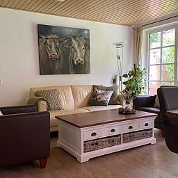 Gemuetliches Wohnzimmer im Ferienhaus in Holten, Overijssel mit komfortabler Sitzecke und grossen Fenstern mit Blick auf die Natur.