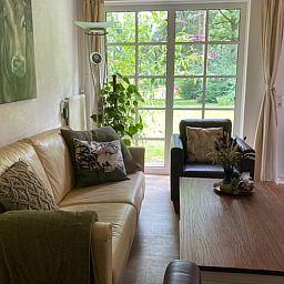 Gemuetliches Wohnzimmer im Ferienhaus in Holten, Overijssel mit Blick auf den gruenen Garten. Ideal fuer einen entspannten Aufenthalt in Salland.