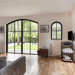 Helles Wohnzimmer von Huisje in Holten, Ferienhaus in Salland, Overijssel mit Blick auf den gruenen Garten durch grosse Fenster.