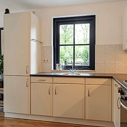 Moderne Kueche im Huisje in Holten, einem Ferienhaus im gruenen Salland, Overijssel, mit Blick aus dem Fenster auf den Garten.