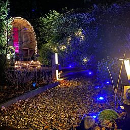 Sfeervol verlicht pad naar het Vakantiehuisje in Holten, omgeven door natuur in Salland, Overijssel, ideaal voor een romantisch verblijf.