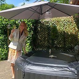 Geniet van ontspanning in de tuin van Vakantiehuisje in Holten, gelegen in het groene Salland, Overijssel, met een luxe jacuzzi onder een parasol.