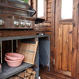 Buitenkeuken van Vakantiehuisje in Wesepe, Salland, Overijssel met barbecue en houten opbergruimte voor een gezellige vakantie-ervaring.