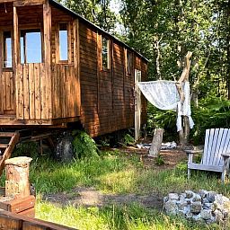 Charmant vakantiehuisje in Wesepe, Salland, Overijssel omringd door natuur met houten veranda en zitplek voor een ontspannen verblijf.