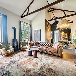 Stijlvolle woonkamer in Vakantiehuis in Diepenveen, met comfortabele zithoek en uitzicht op de groene omgeving.