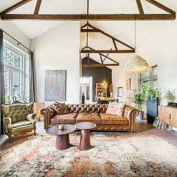 Ruime woonkamer in Vakantiehuis in Diepenveen, met hoge plafonds en een prachtig uitzicht op de tuin.