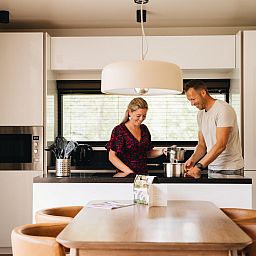 Ein Ehepaar in der Kueche des Ferienhauses Hill Lodge, Beerze, geniesst einen entspannten Moment.