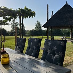 Sonnige Terrasse des Ferienhauses in Beerze, Region Vecht, Overijssel, mit Blick auf die laendliche Umgebung und den Pavillon.