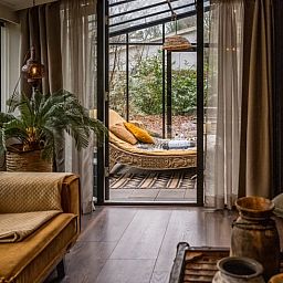 Stilvolles Wohnzimmer des Ferienhauses in Rheezerveen, Vechtstreek, Overijssel mit moderner Einrichtung und Zugang zum Wintergarten.