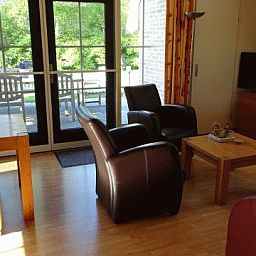 Gezellige woonkamer in vakantiehuis AA-Reestryck, IJhorst, Overijssel met uitzicht op groene tuin en ruime zithoek.