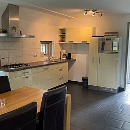 Moderne Kueche im Ferienhaus in Lemele, Vechtstreek, Overijssel mit geraeumiger Essecke und Blick auf die gruene Umgebung.