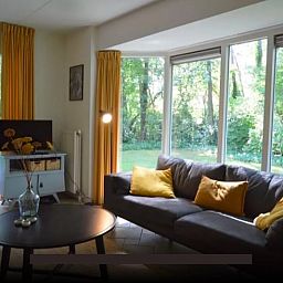 Lichte woonkamer van vakantiehuis Huisje in Lemele, Overijssel met grote ramen en groene omgeving.