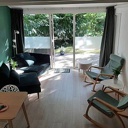 Gemuetliches Wohnzimmer des Ferienhauses in Stegeren, umgeben von Natur in der Region Vecht, Overijssel, mit grossem Fenster und bequemer Sitzecke.