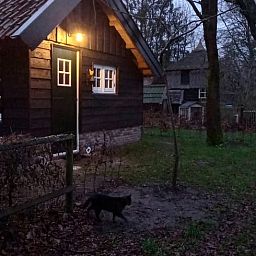 Sfeervol verlicht vakantiehuis in Brucht, Vechtstreek, Overijssel in de avondschemering.