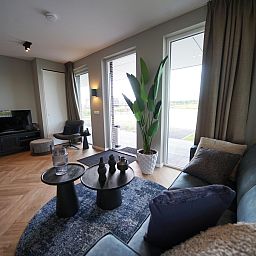 Stilvolles Wohnzimmer in einer Wohnung in Kampen, Overijssel, mit moderner Einrichtung und Blick auf die grne Umgebung.