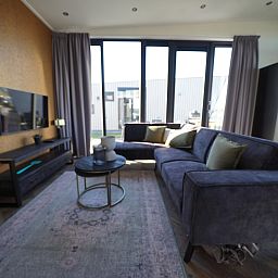 Gemtliches Wohnzimmer im freistehenden Haus in Kampen, Nordwest-Overijssel, mit bequemem Sofa und groen Fenstern fr viel Licht.