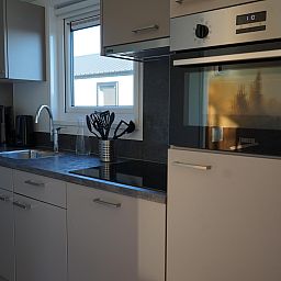 Moderne Kche in einem Einfamilienhaus in Kampen, Overijssel, mit schlichtem Design und Blick auf die Umgebung.