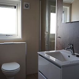 Modernes Badezimmer im freistehenden Haus in Kampen, Overijssel, mit schlichtem Waschbecken und gerumiger Dusche fr einen komfortablen Aufenthalt.
