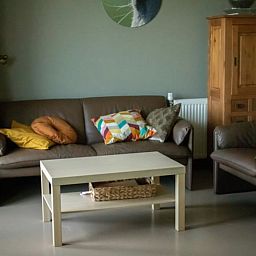 Gezellige woonkamer in Huisje in Steenwijk, vakantiehuis in Noordwest Overijssel, met comfortabele banken en kleurrijke kussens.