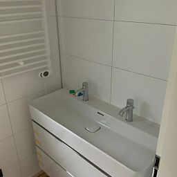 Moderne badkamer in Vrijstaande woning in IJhorst, Noordwest Overijssel, met dubbele wastafel en strakke witte tegels.