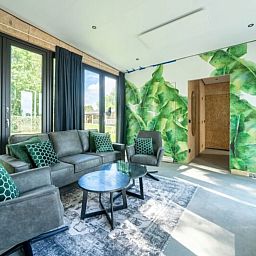 Modernes Wohnzimmer in einem freistehenden Haus in IJhorst, Overijssel, mit grnen Akzenten und Blick auf den Garten.